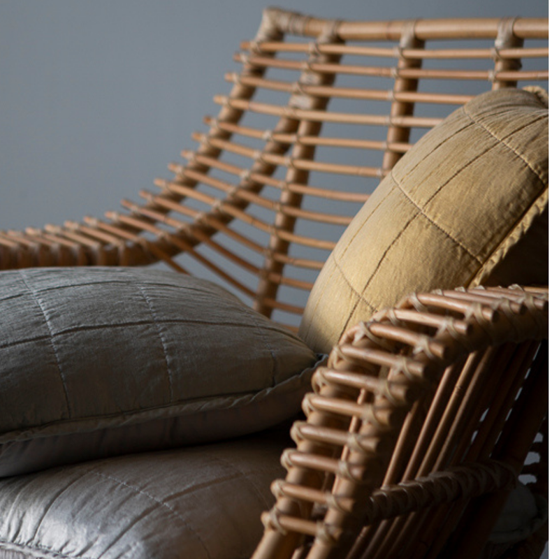 Sel Throw Pillow | a close up of quilted charmeuse throw pillows in a rattan chair.