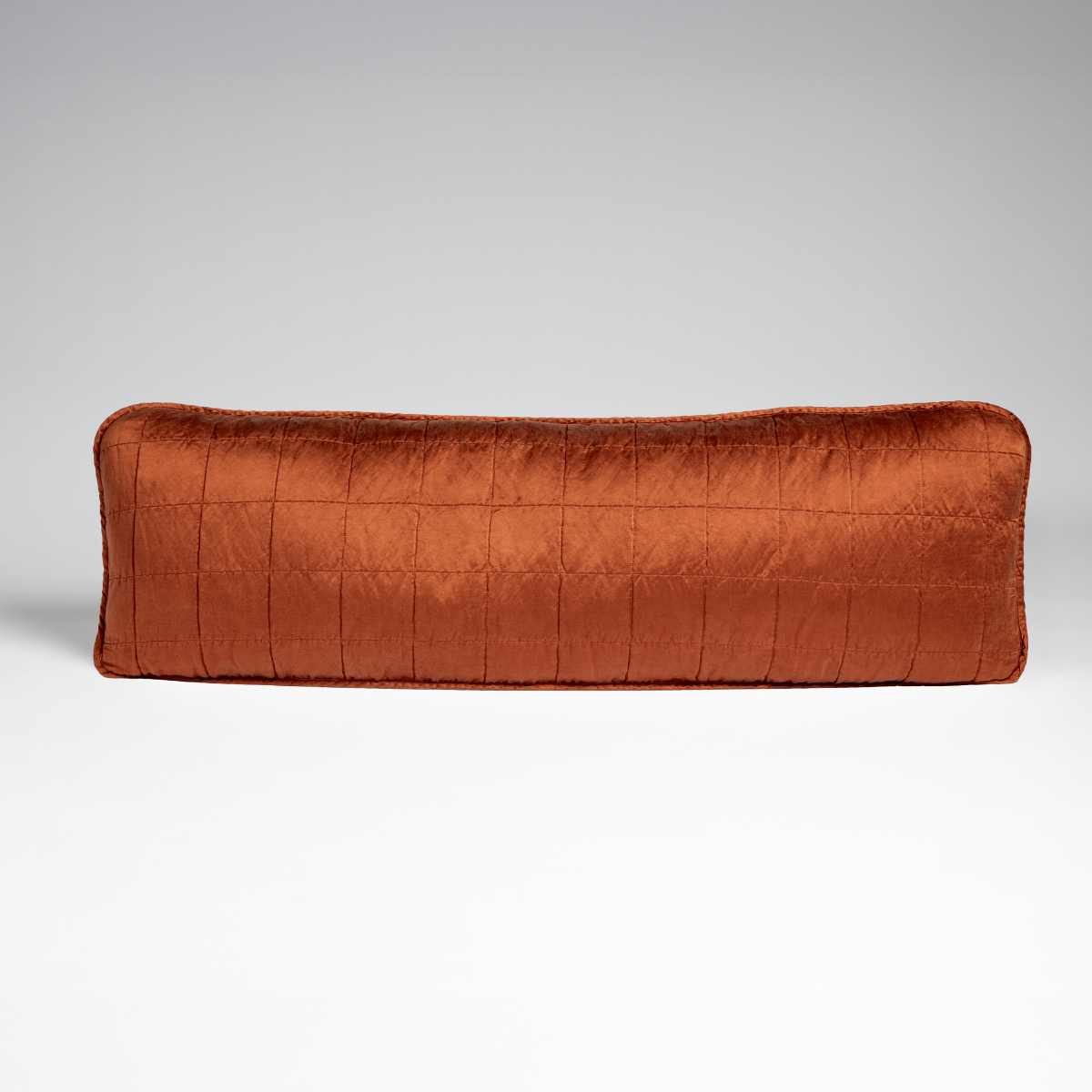 Sel Throw Pillow | Autumn | A straight-on shot of a square-quilted body pillow in autumn, a rich terracotta tone, against a white background.