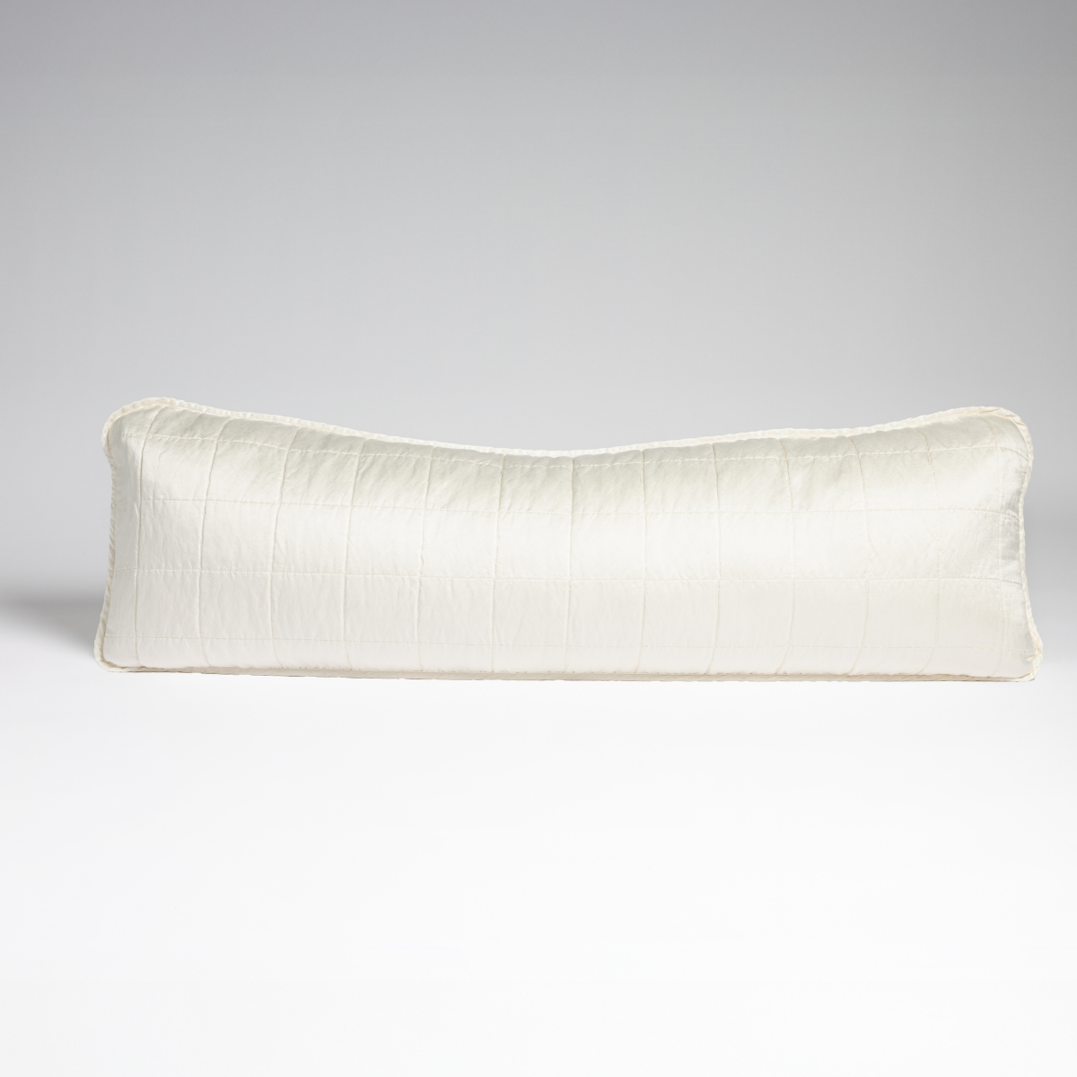 Sel Throw Pillow | Winter White | A straight-on shot of a square-quilted body pillow in winter white, a softer and warmer tone than our classic white, against a white background.