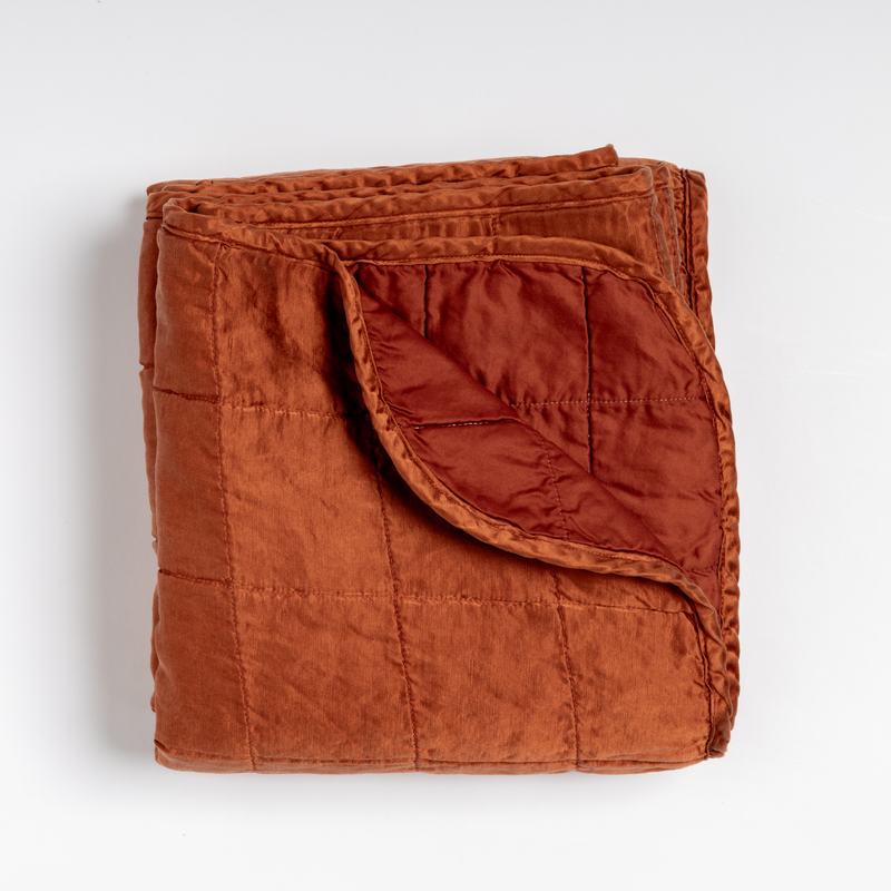Sel Blanket | Autumn | an overhead shot of a quilted charmeuse blanket with a corner folded down, showing its cotton sateen back.