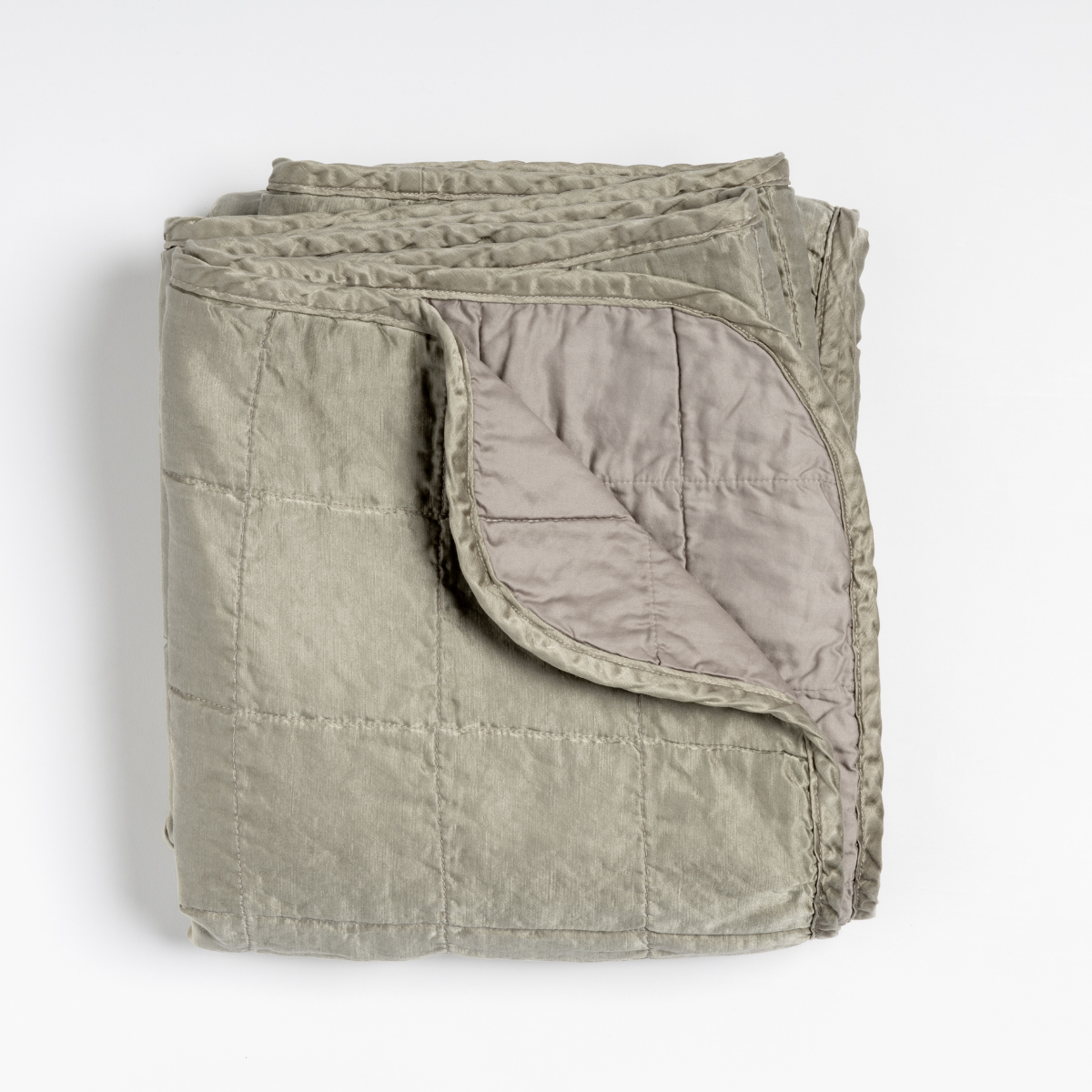 Sel Blanket | Fog | an overhead shot of a quilted charmeuse blanket in fog, a soft mid-tone grey, with a corner folded down, showing its cotton sateen back.