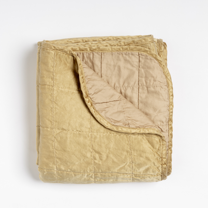 Sel Blanket | Honeycomb | an overhead shot of a quilted charmeuse blanket in honeycomb, a warm golden tone, with a corner folded down, showing its cotton sateen back.