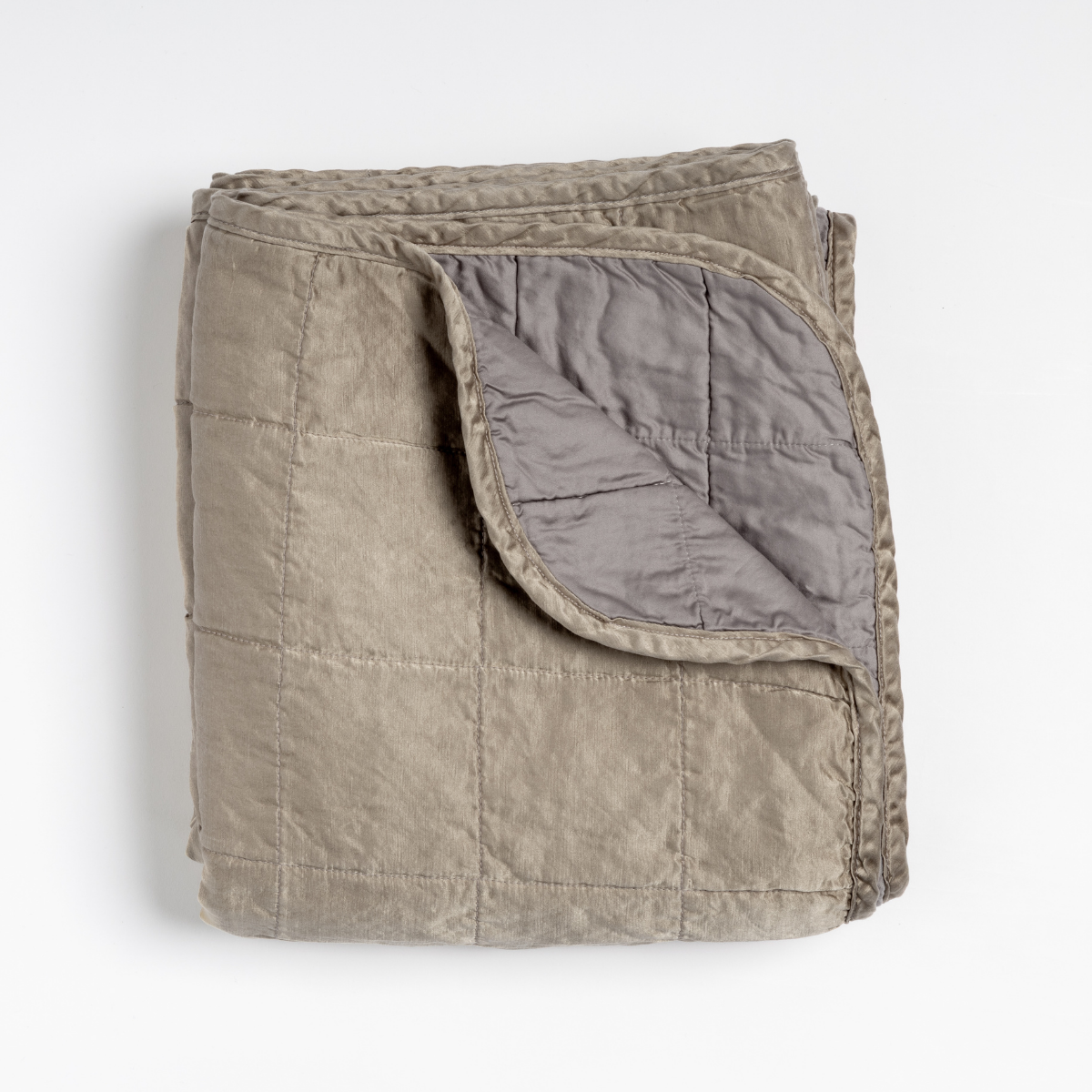 Sel Blanket | Moonlight | an overhead shot of a quilted charmeuse blanket in moonlight, a saturated, cool, mid-dark grey tone, with a corner folded down, showing its cotton sateen back.