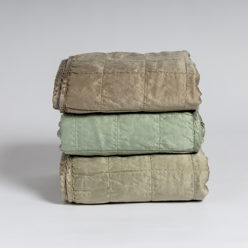 Sel Blanket | A stack of three square-quilted charmeuse blankets shot straight on against a white background. 