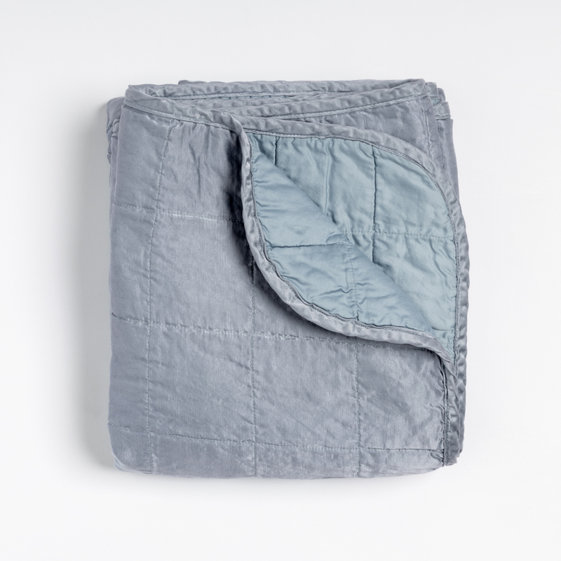 Sel Blanket | Tahoe Blue | an overhead shot of a quilted charmeuse blanket in tahoe blue, a crisp true blue, with a corner folded down, showing its cotton sateen back.