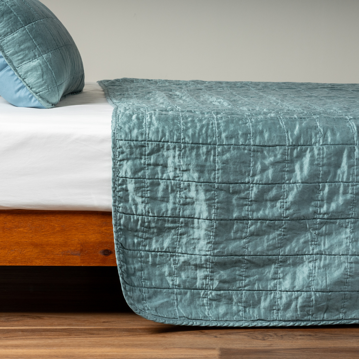 Sel Coverlet | Cenote | A side shot of a square quilted charmeuse coverlet in cenote, a vibrant ocean-inspired blue-green, with its matching sham.