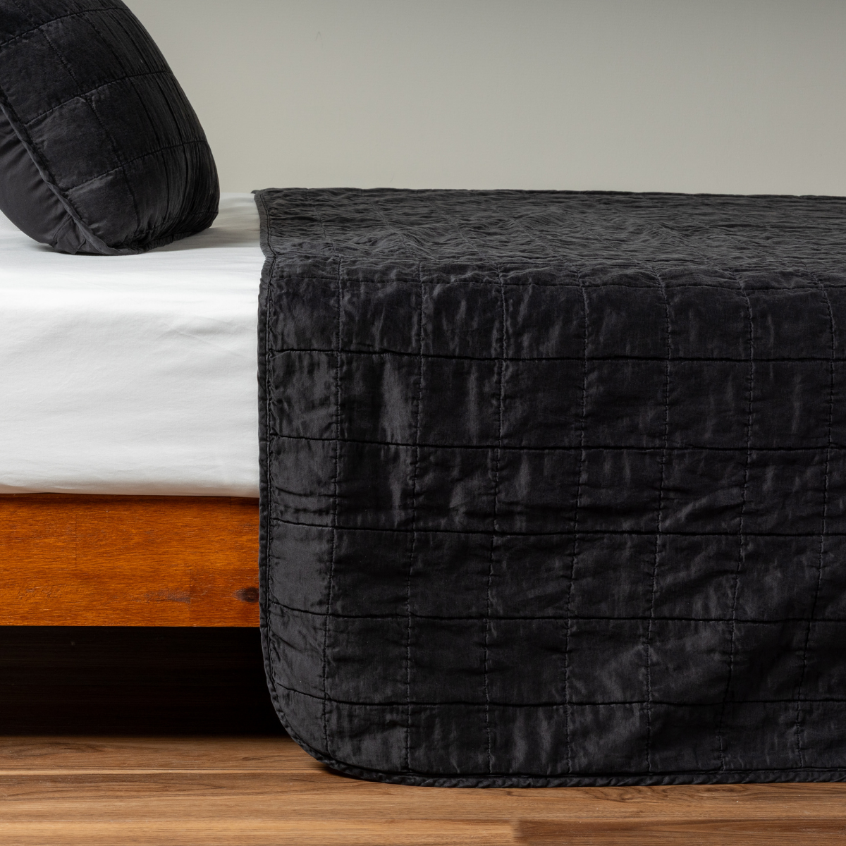 Sel Coverlet | Corvino | A side shot of a square quilted charmeuse coverlet in corvino, a classic black, with its matching sham.