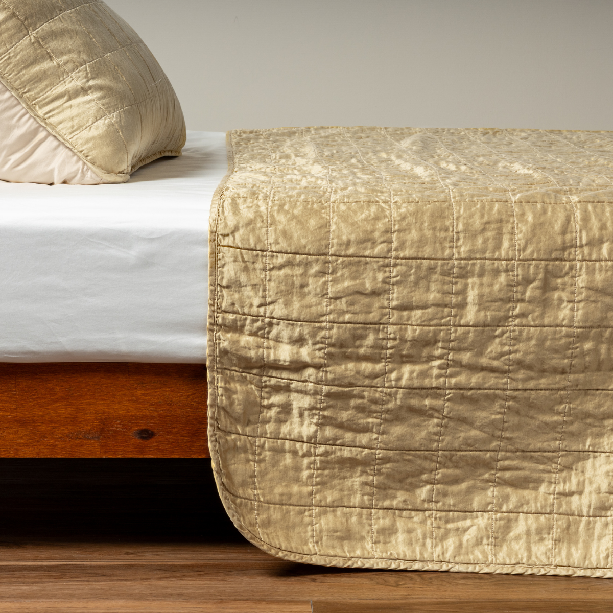 Sel Coverlet | Honeycomb | A side shot of a square quilted charmeuse coverlet in honeycomb, a warm golden tone, with its matching sham.