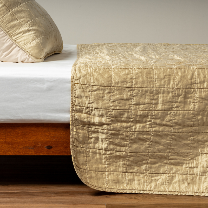 Sel Coverlet | Honeycomb | A side shot of a square quilted charmeuse coverlet in honeycomb, a warm golden tone, with its matching sham.