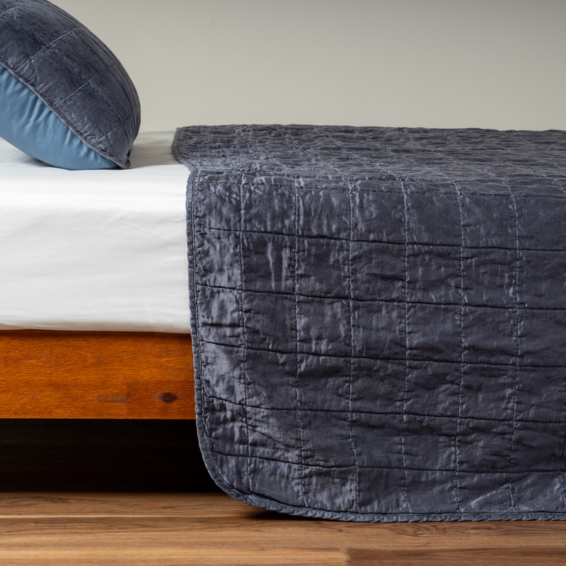 Sel Coverlet | Midnight | A side shot of a square quilted charmeuse coverlet in midnight, a rich indigo tone, with its matching sham.