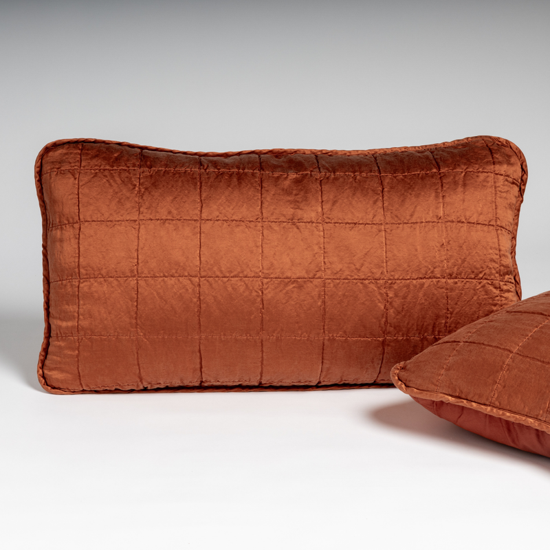 Sel Sham | Autumn | A pair of shams in autumn, a rich terracotta tone, shown against a white background with one sham upright and the other on its side to show the cotton sateen back and square-quilted charmeuse front.