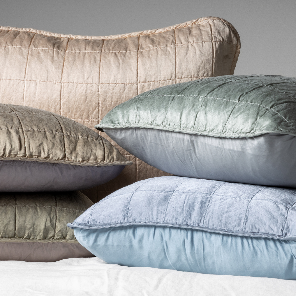 Sel Sham | A cluster shot of five charmeuse shams showing their square quilt patterned fronts and unquilted backs.