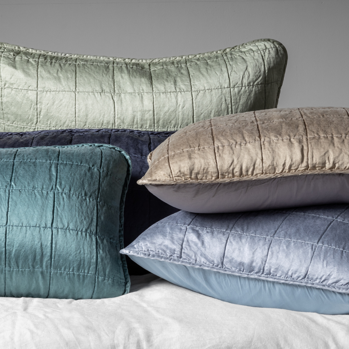Sel Sham | A cluster shot of five square-quilted charmeuse shams showing their unquilted cotton sateen back. 
