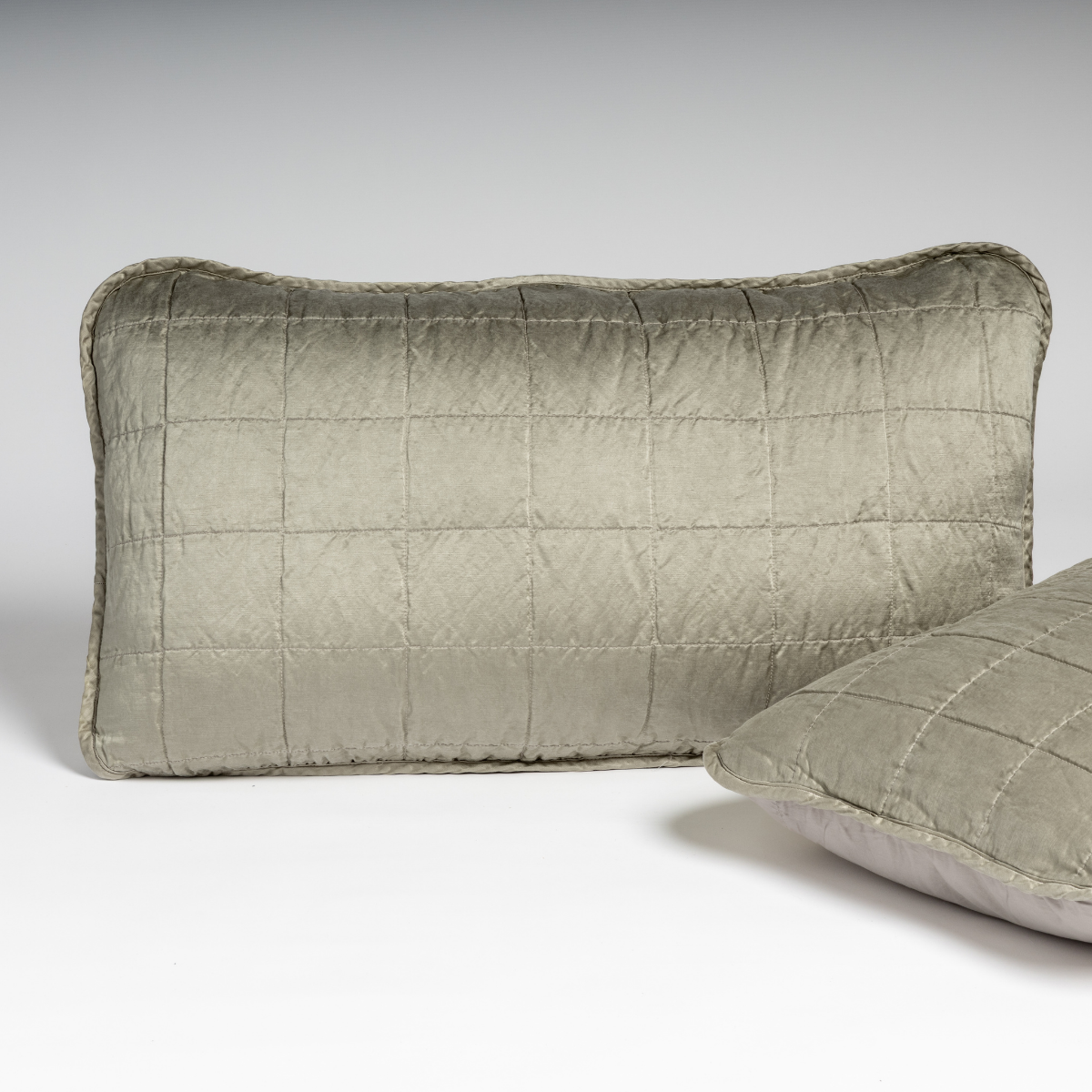 Sel Sham | Fog | A pair of shams shown in fog, a soft mid-tone grey, against a white background with one sham upright and the other on its side to show the cotton sateen back and square-quilted charmeuse front.