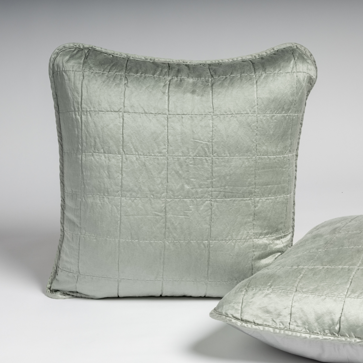Sel Sham | Mineral | A pair of shams shown in mineral, a soothing seafoam blue with subtle grey-green undertone, against a white background with one sham upright and the other on its side to show the cotton sateen back and square-quilted charmeuse front.