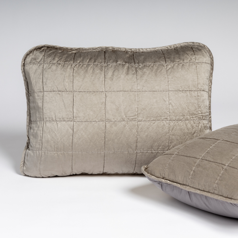 Sel Sham | Moonlight | A pair of shams in moonlight, a saturated, cool, mid-dark grey tone, shown against a white background with one sham upright and the other on its side to show the cotton sateen back and square-quilted charmeuse front.