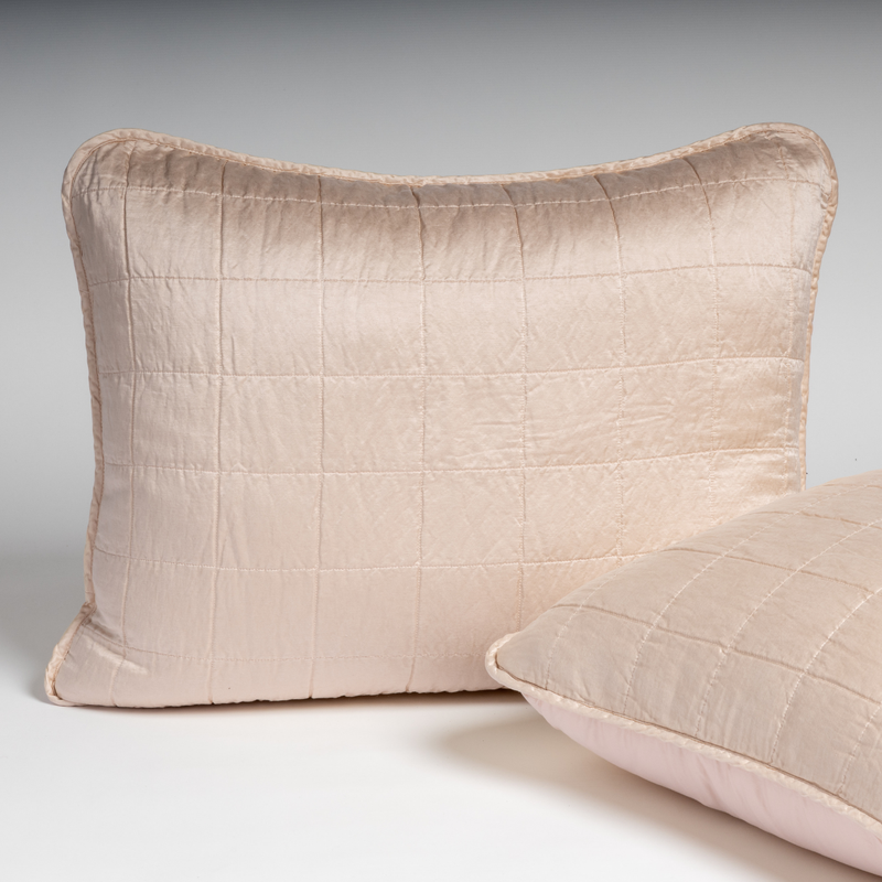Sel Sham | Pearl | A pair of shams in pearl, a soft rose pink tone, shown against a white background with one sham upright and the other on its side to show the cotton sateen back and square-quilted charmeuse front.