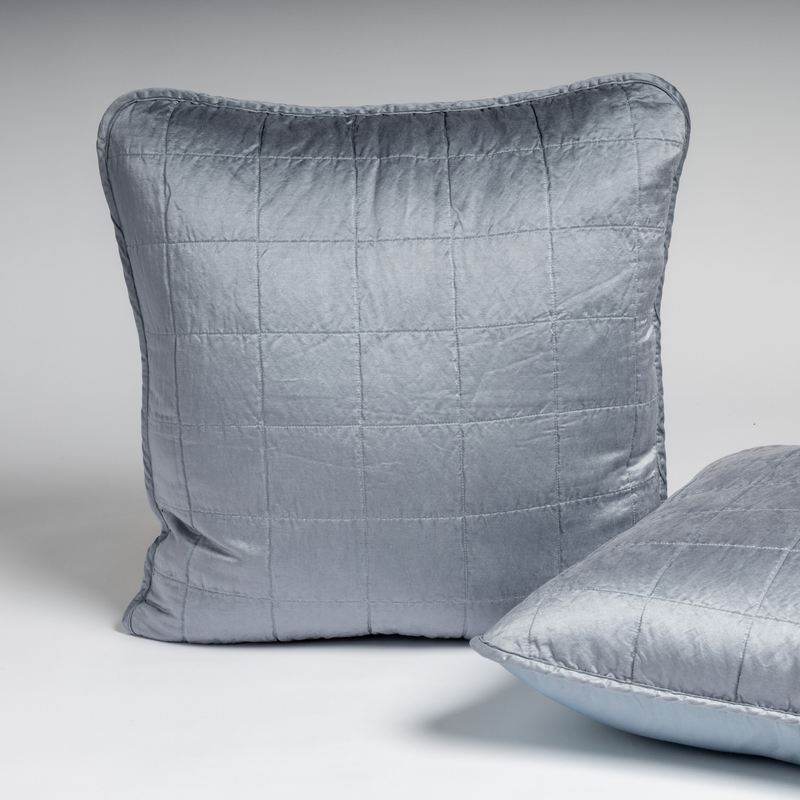 Sel Sham | Tahoe Blue | A pair of Euro shams shown in tahoe blue, a crisp true blue, against a white background with one sham upright and the other on its side to show the cotton sateen back and square-quilted charmeuse front.