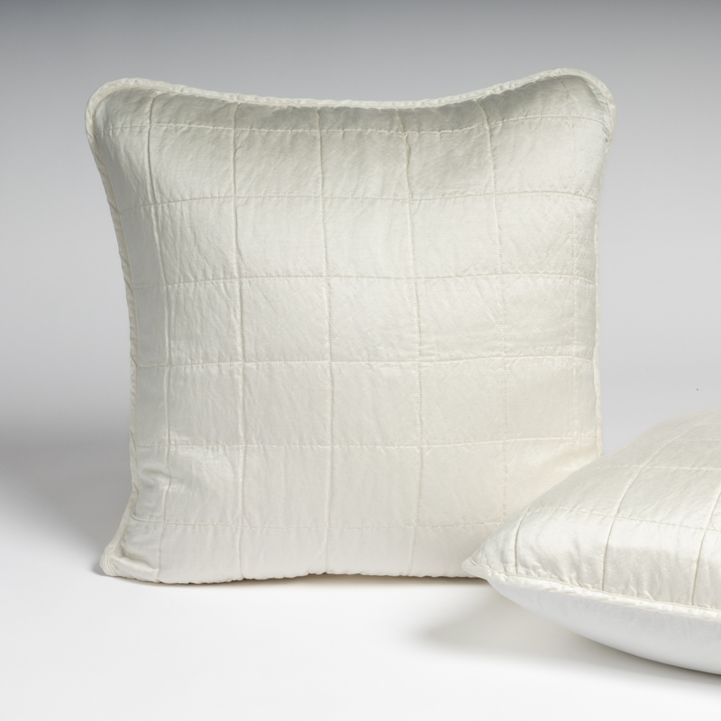 Sel Sham | Winter White | A pair of shams shown in winter white, a softer and warmer tone than our classic white, against a white background with one sham upright and the other on its side to show the cotton sateen back and square-quilted charmeuse front.