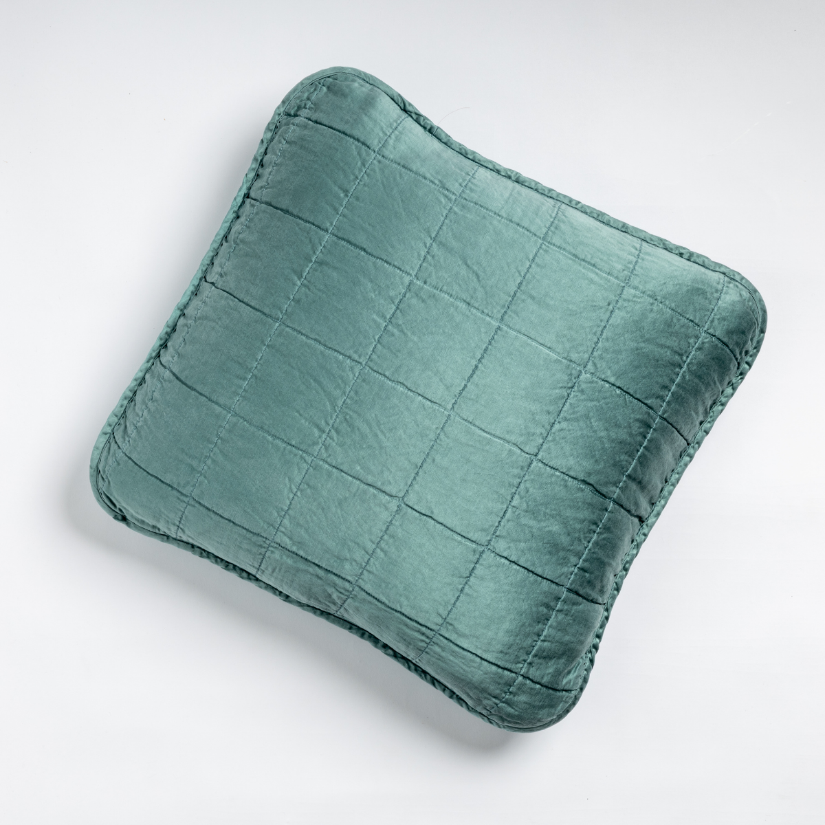 Sel Throw Pillow | Cenote | An overhead shot of a square-quilted square throw pillow in cenote, a vibrant ocean-inspired blue-green, against a white background.