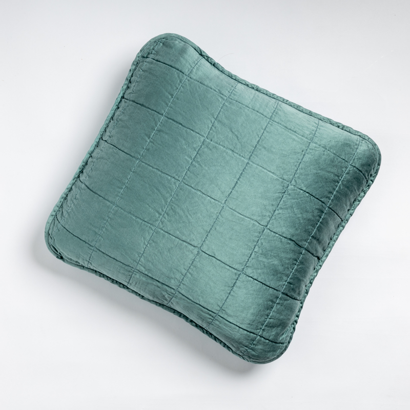 Sel Throw Pillow | Cenote | An overhead shot of a square-quilted square throw pillow in cenote, a vibrant ocean-inspired blue-green, against a white background.