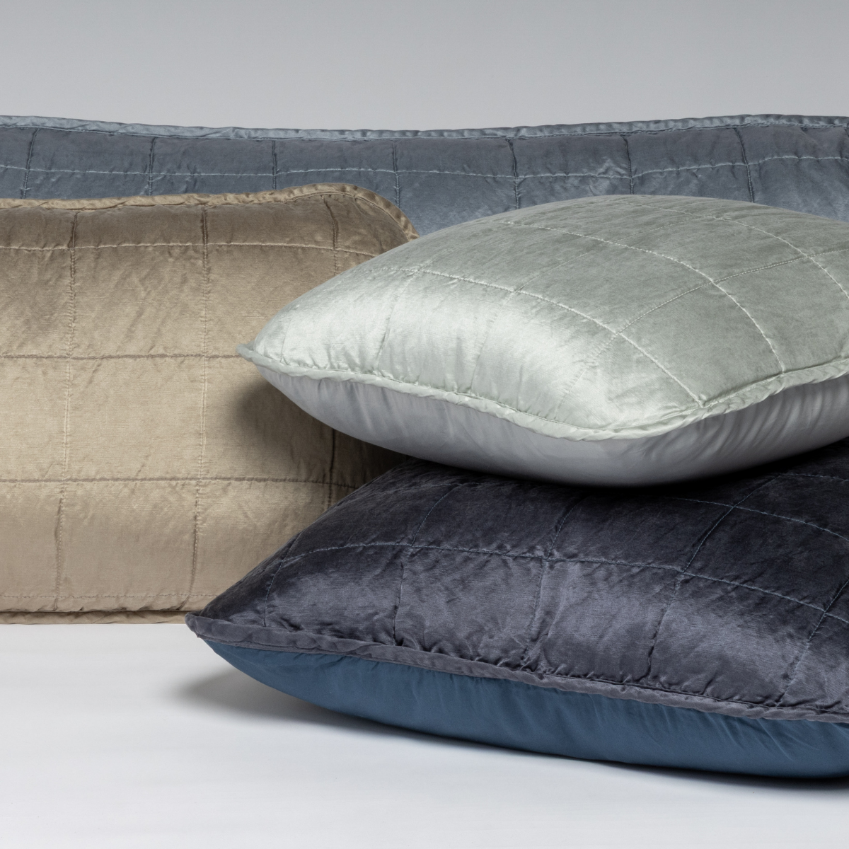 Sel Throw Pillow | A cluster shot of four square-quilted charmeuse shams showing their unquilted cotton sateen back.