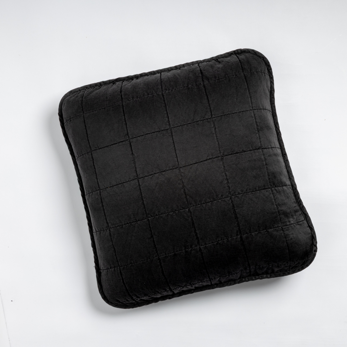Sel Throw Pillow | Corvino | An overhead shot of a square-quilted square throw pillow in corvino, our classic black, against a white background.