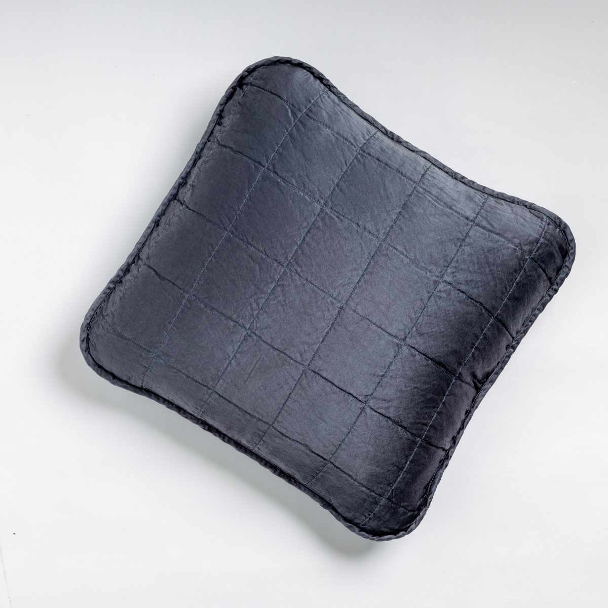 Sel Throw Pillow | Midnight | An overhead shot of a square-quilted square throw pillow in midnight, a rich indigo tone, against a white background.
