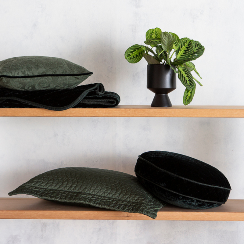 Cirillo Throw Pillow | Juniper | quilted throw pillows on the second shelf shown with other living pieces also in Juniper with a live plant.