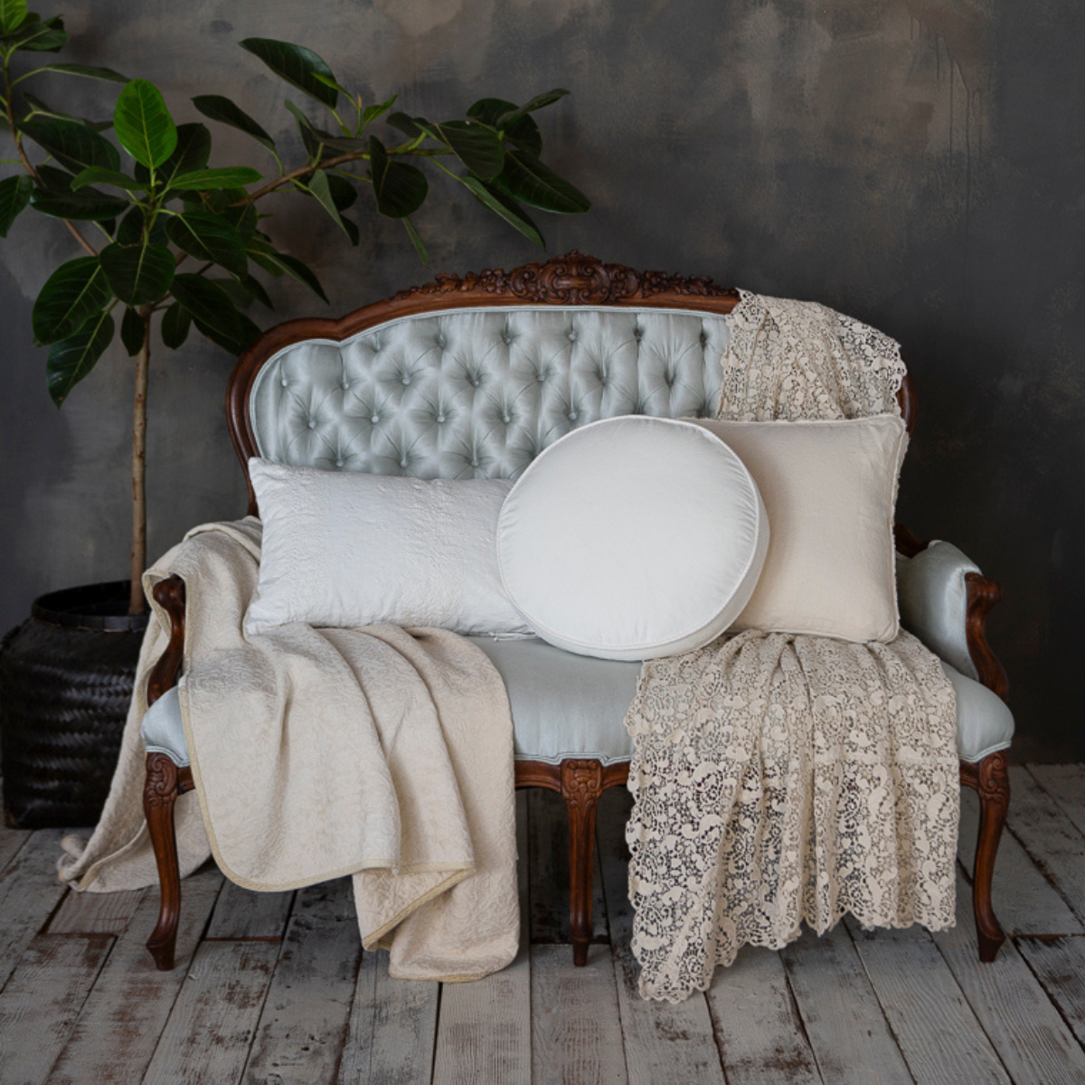 An antique sofa dressed in neutral-toned throw pillows and blankets.