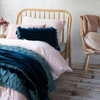Luna Twin Coverlet | Coverlet in cenote layered on a twin bed with soft pink and rich blue green tones - angled view.