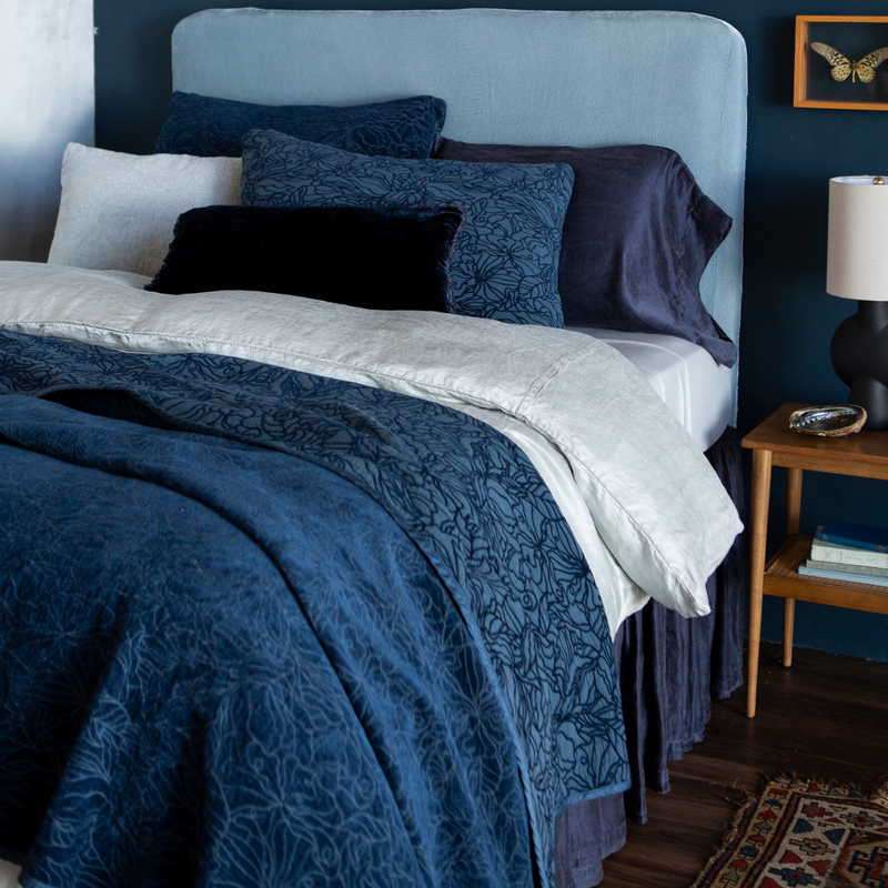 Georgia Bedspread | shot at a three-quarter angle, the fully dressed bed is shown in blue tones in different fabrics showing the tonality and of the hues and pattern on the chenille and cotton jacquard bedspread and shams