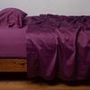 Bria Twin Flat Sheet | Fig | Cotton sateen flat sheet, shown with matching fitted sheet and sleeping pillow - side view.
