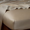 Bria Twin Flat Sheet | Honeycomb | Cotton sateen flat sheet draped over matching fitted sheet. Shown from the top corner, the flat sheet is rumpled, highlighting the shine of the fabric.