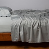 Bria Twin Flat Sheet | Mineral | Cotton sateen flat sheet, shown with matching fitted sheet and sleeping pillow - side view.
