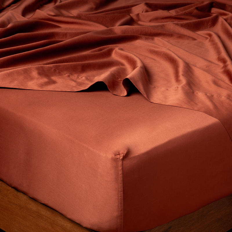 Autumn | A close-up of a bed corner in a Bria fitted sheet in Autumn, a rich terracotta tone.