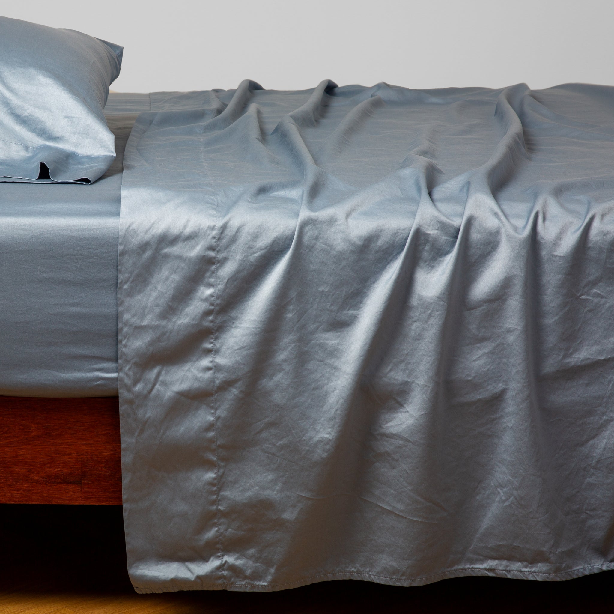 Bria Standard Pillowcase (Single) | Tahoe Blue | Cotton sateen fitted sheet shown with matching flat sheet and sleeping pillow - side view.