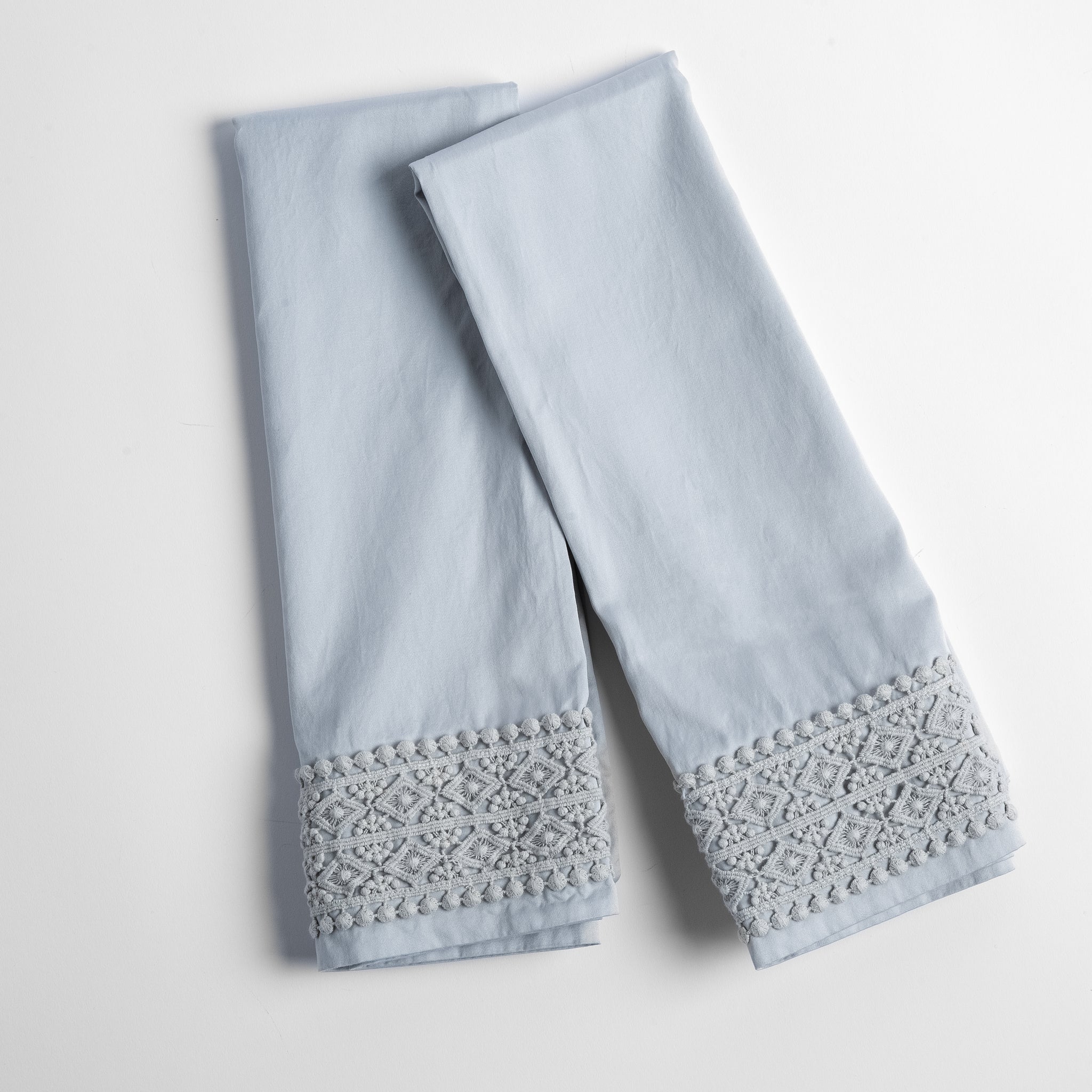 Bria Pillowcase (Single) | Cloud | a pair of folded cotton sateen pillowcases with cotton lace on the cuff, shown from overhead against a white background.