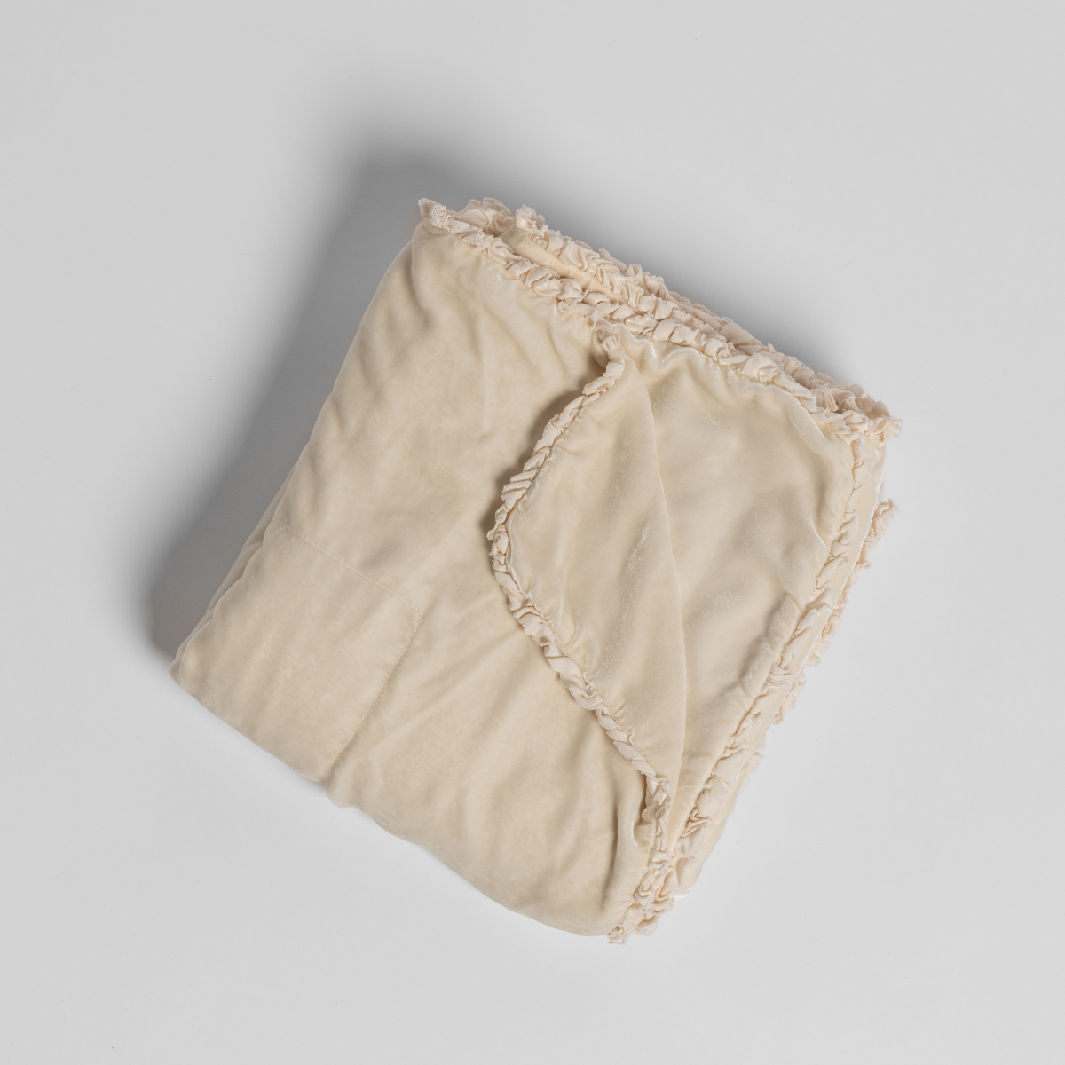 Carmen Blanket | Crema | silk velvet unfilled throw blanket with a petite charmeuse ruffle trim, overhead on a white background.