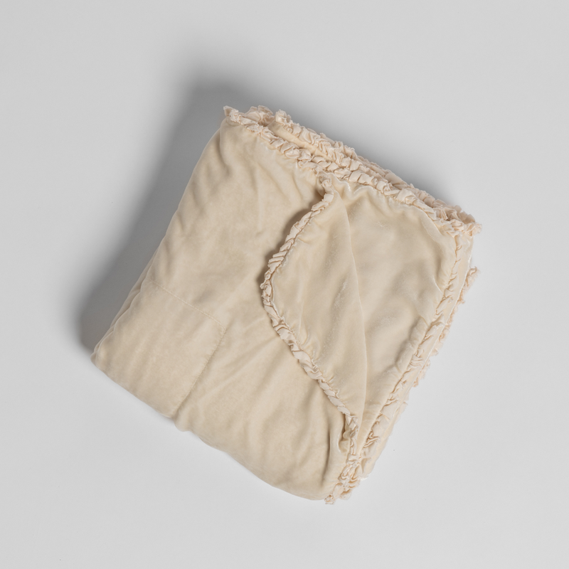 Carmen Blanket | Crema | silk velvet unfilled throw blanket with a petite charmeuse ruffle trim, overhead on a white background.