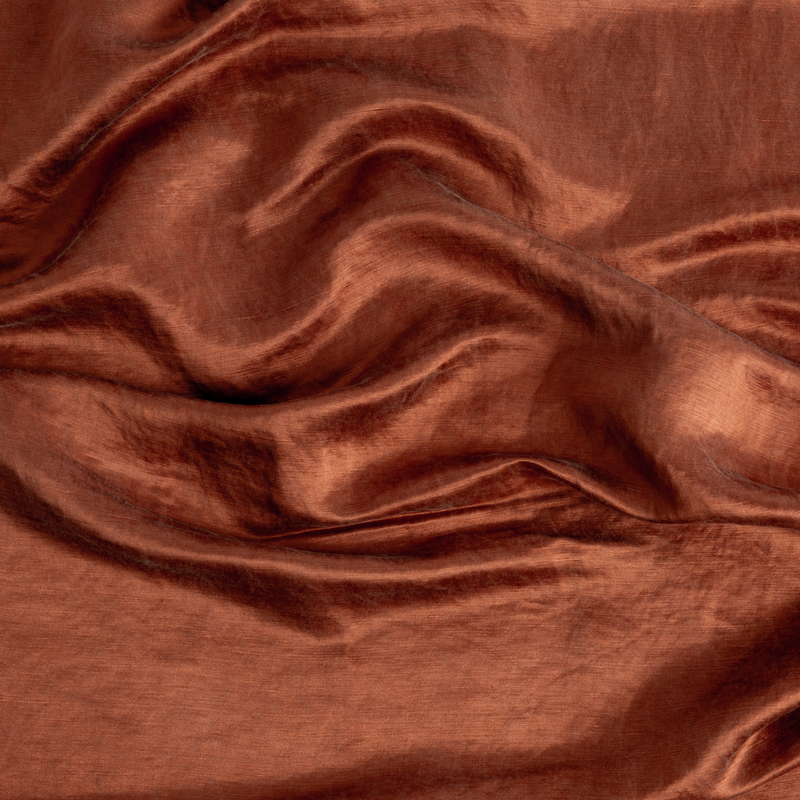 Paloma Sham | Autumn | A close-up of Charmeuse fabric gently rumpled in the colorway, Autumn, a rich terracotta tone.