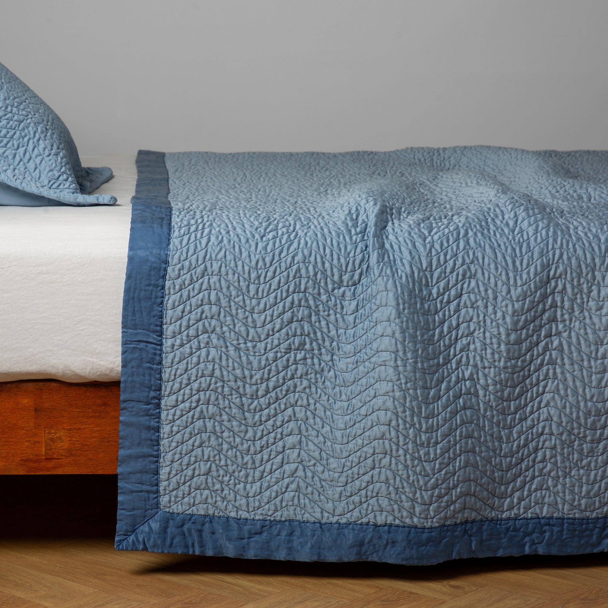 Cirillo Coverlet | Tahoe Blue | quilted cotton sateen coverlet with matching sham on a winter white fitted sheet - side view.