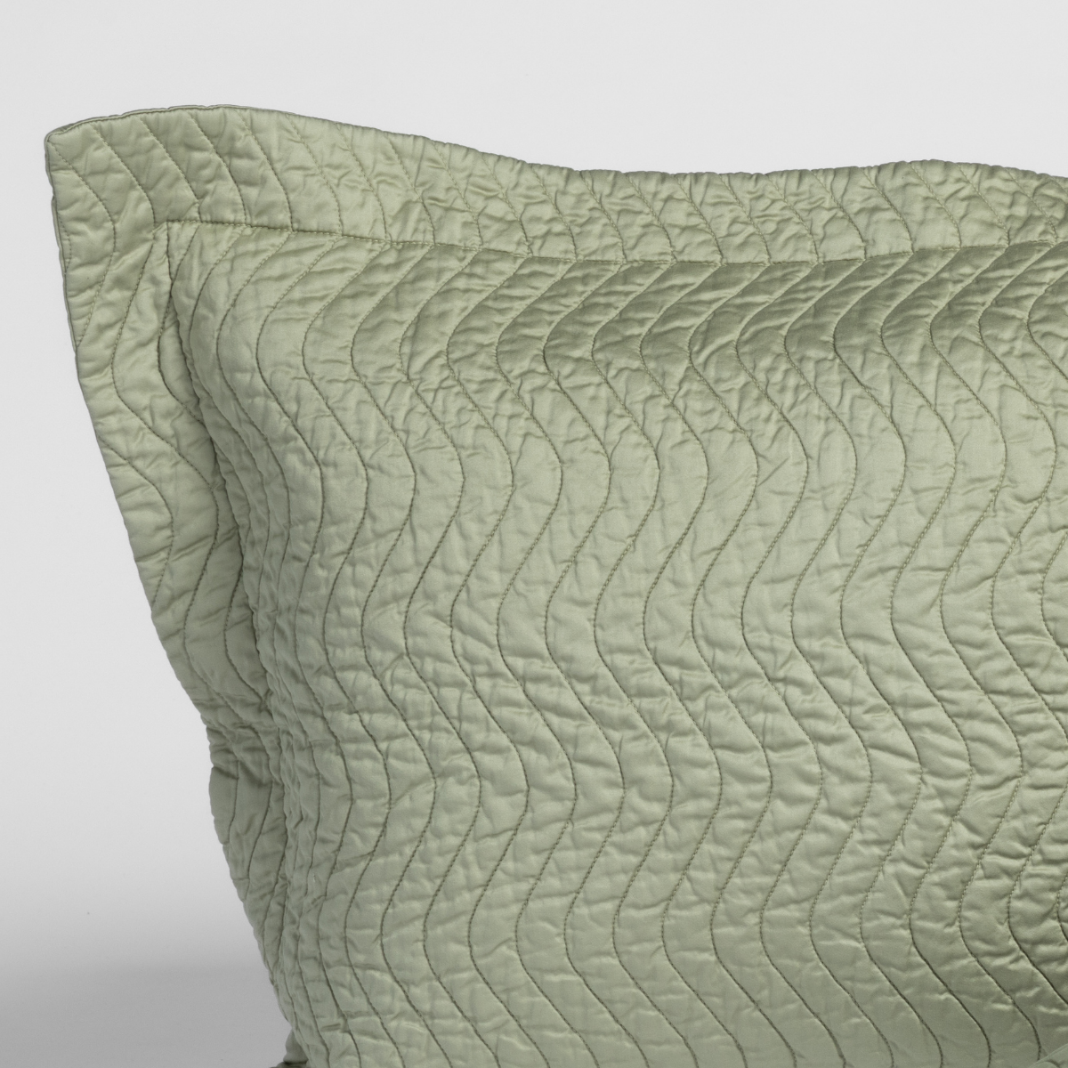 Cirillo Throw Pillow | Desert Sage | close up of a pillow corner in desert sage, a serenely elegant green, offering a hushed hue, shown against a plain background.