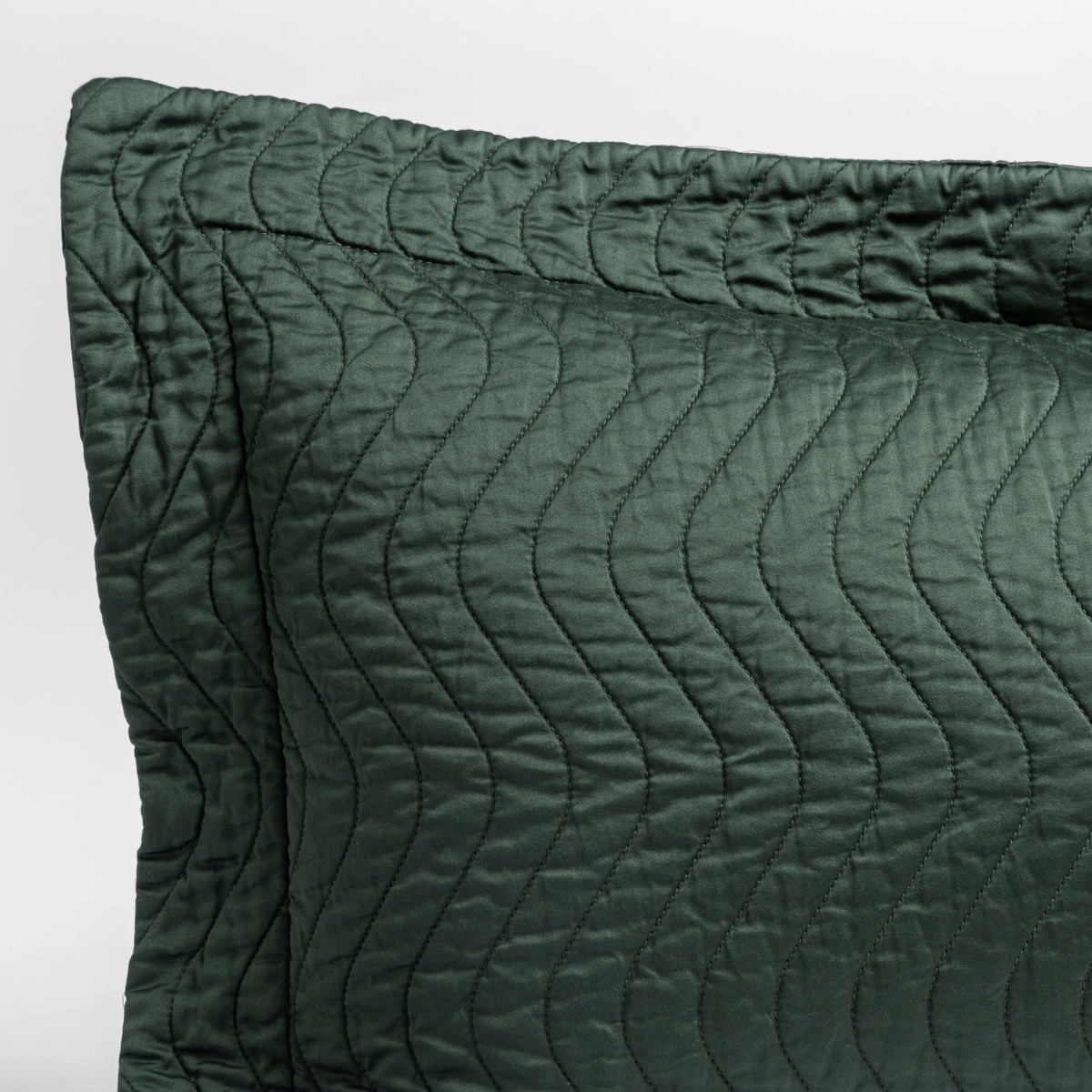 Cirillo Throw Pillow | Juniper | a close up of a pillow corner showing the flange framing quilted cotton sateen shot against a white background.