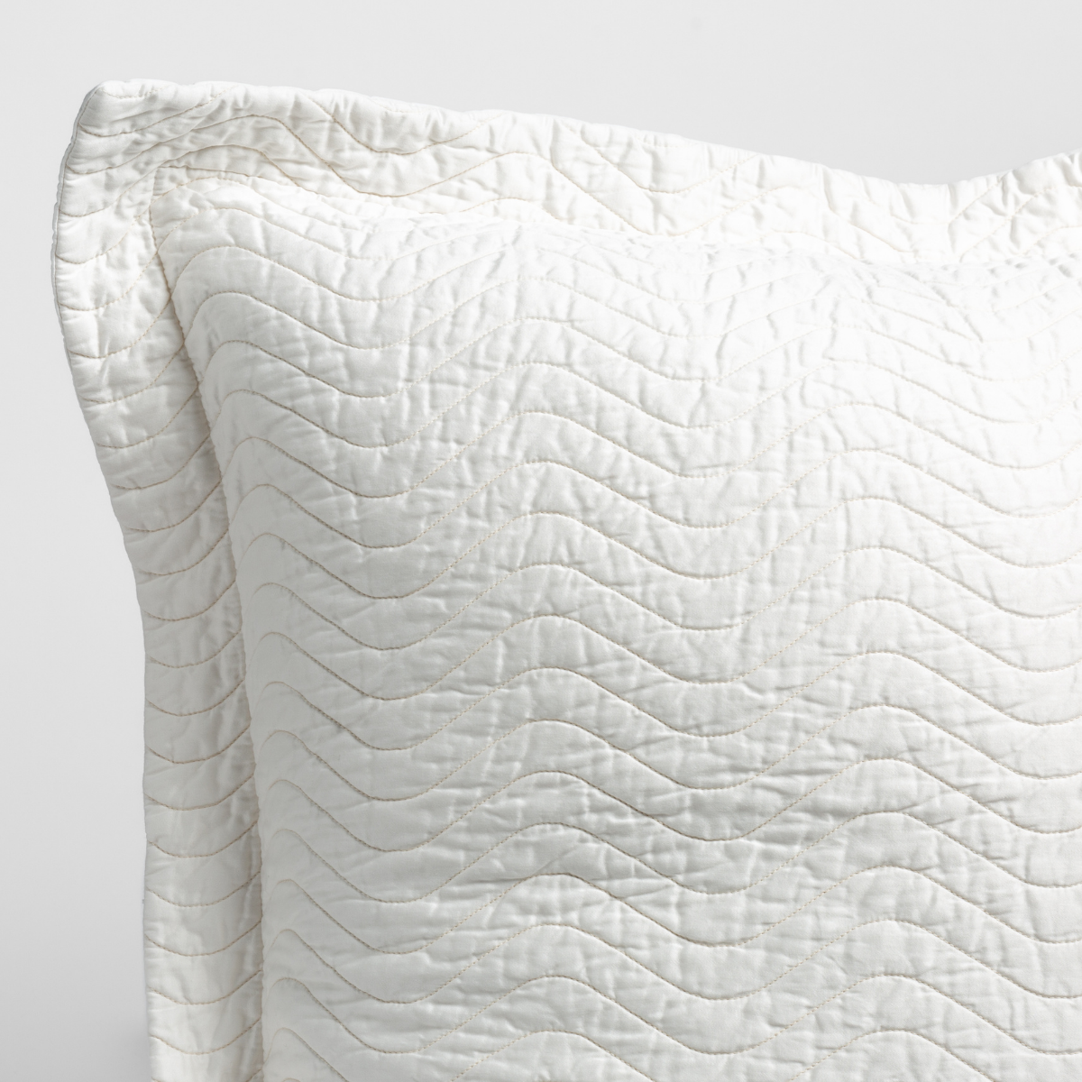 Cirillo Throw Pillow | Winter White | a close up of a pillow corner showing the flange framing quilted cotton sateen shot against a white background.