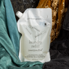 a bottle of unscented common good laundry detergent nested in charmeuse and silk velvet fabrics in various colors.