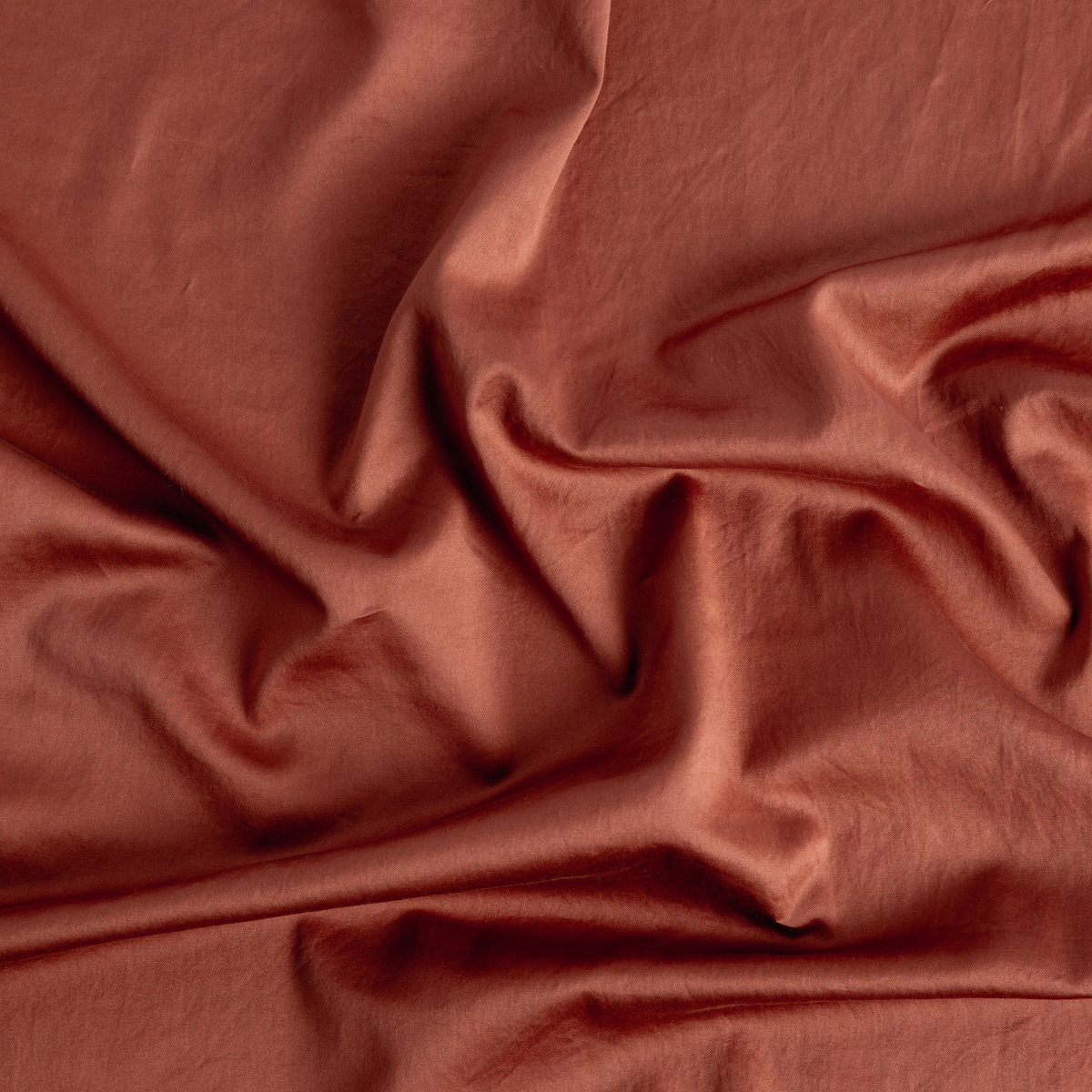 Bria Standard Pillowcase (Single) | Autumn | A close-up of Cotton Sateen fabric gently rumpled in the colorway, Autumn, a rich terracotta tone.