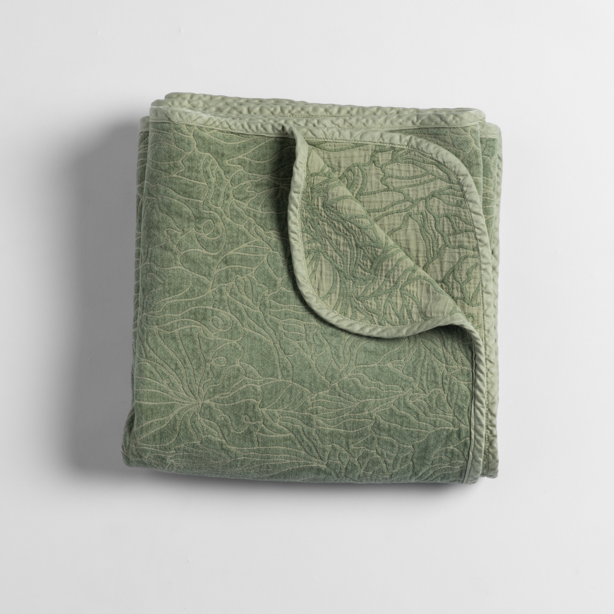 Georgia Blanket | Desert Sage | an overhead shot of a folded blanket in desert sage, a serenely elegant green, offering a hushed hue, shown against a plain background.