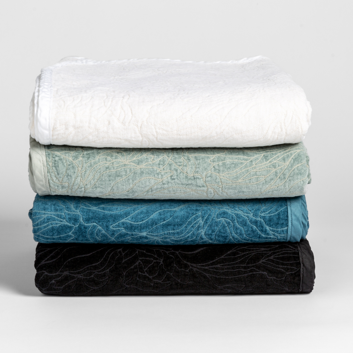 Georgia Blanket | a stack of four blankets folded with their chenille jacquard sides facing outward and the cotton sateen trim subtle and tonal.