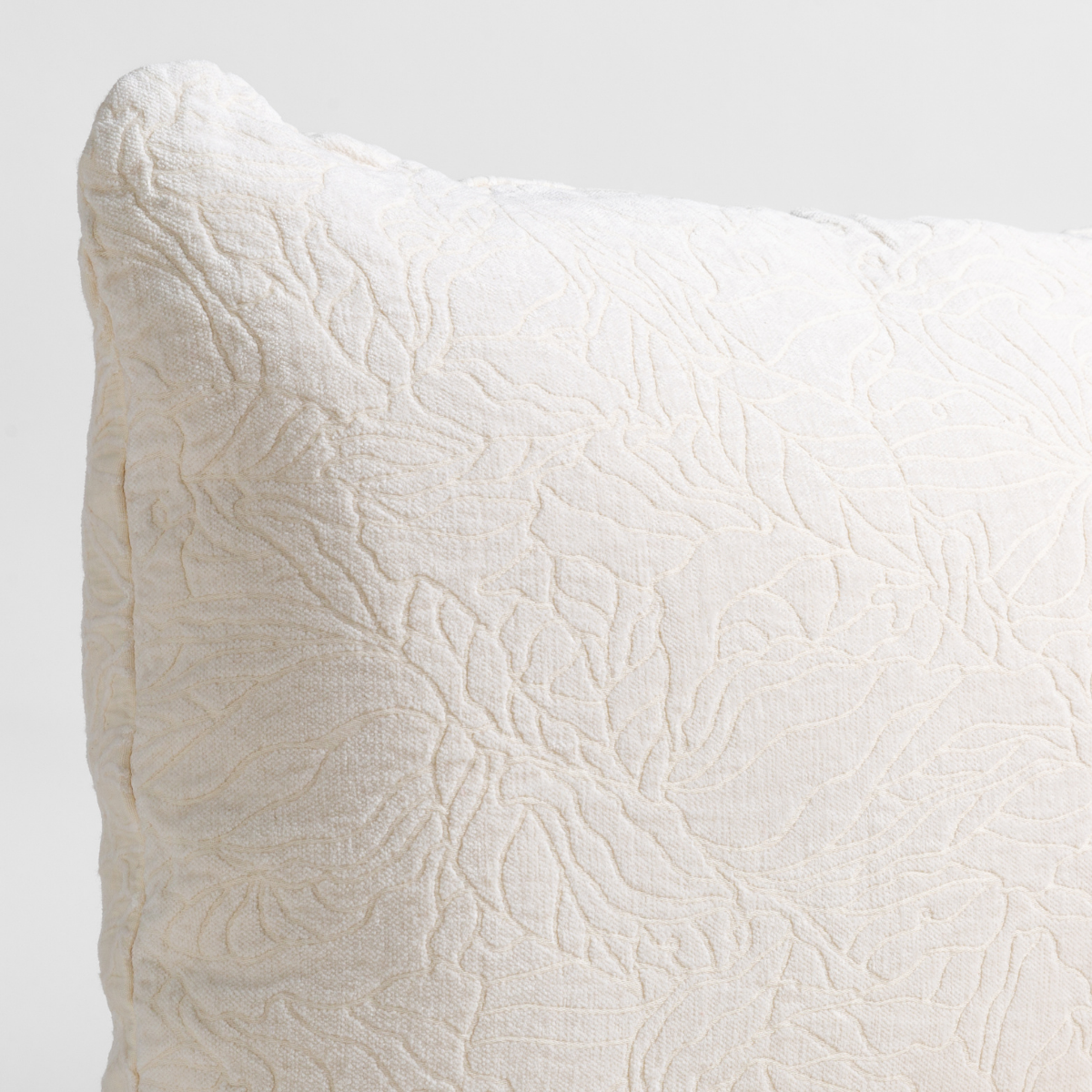 Georgia Throw Pillow | Winter White | close up of the chenille jacquard corner of a pillow cushion with a single-line floral pattern.